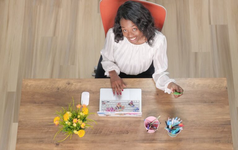 a woman in white long sleeves sitting near the wooden table with laptop
